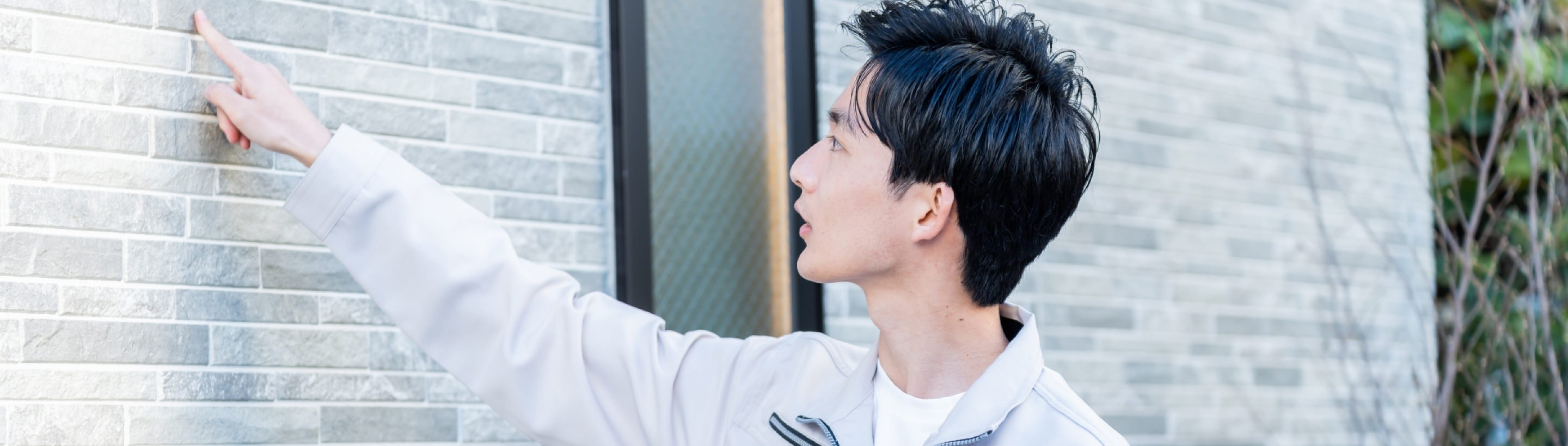 画像：壁の外壁を調査する男性スタッフ